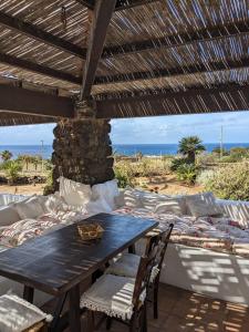 una mesa y sillas de madera bajo un techo de madera en The Place Yoga Retreat *FREE YOGA CLASS en Pantelleria