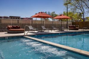 a swimming pool with two chairs and umbrellas at River Canyon Lodge in Moab
