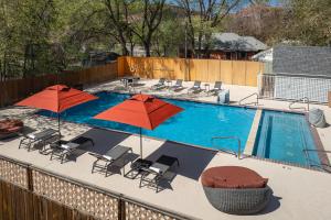 a swimming pool with two umbrellas and chairs at River Canyon Lodge in Moab