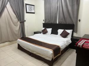 a bedroom with a bed with white sheets and brown pillows at شقق ذوق الخيآل المخدومه الحبله in Abha