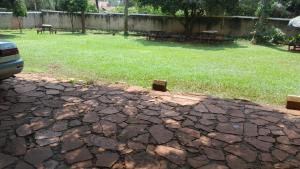 a yard with a field of grass with picnic tables at Meral inn Jinja in Jinja