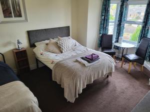um quarto com uma cama, 2 cadeiras e uma janela em Station Guesthouse em Lancaster