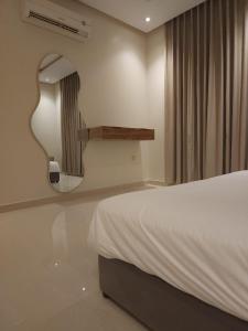 een slaapkamer met een wit bed en een spiegel bij Cozy one bedroom apartment in Riyad