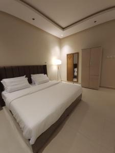 een groot wit bed in een kamer met een lamp bij Cozy one bedroom apartment in Riyad