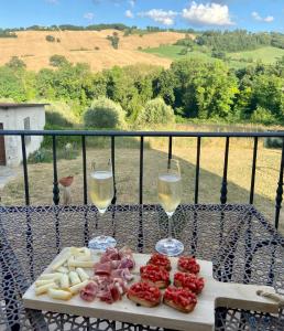 a table with two glasses of white wine and cheese at B&B Casa Contento in Arcevia