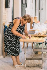 a woman in a black and white dress preparing food on a table at Lena's Suites Bari Vecchia in Bari