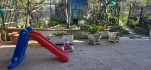 un parco giochi con scivolo rosso e piante in vaso di The Middle House a Castellammare di Stabia