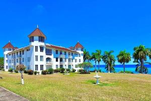 een groot wit gebouw met palmbomen voor de oceaan bij Palm JA SCA31 - Relaxing 1 BR with Beach & Pool Access in Montego Bay