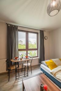 a living room with a table and a bed and a window at Mistrzejowice Studio - Park, Tram & Bus nearby - by Rentujemy in Krakow
