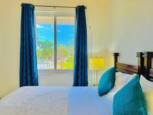 een slaapkamer met een bed met blauwe gordijnen en een raam bij Palm JA SCA31 - Relaxing 1 BR with Beach & Pool Access in Montego Bay