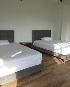 two beds in a room with wooden floors at HOTEL PURA VIDA in Santa Rosa de Cabal
