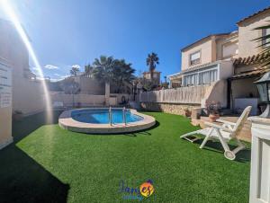 un patio trasero con piscina y césped verde en Cheerful 3 Bedroom Townhouse in El Galan EG2 en San Miguel de Salinas