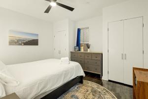 1BR City Park Stay Medical District 30 Day في دنفر: غرفة نوم بيضاء مع سرير ومروحة سقف