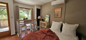a bedroom with a bed and a desk and a window at Mini Caseddu T2, Alba Rossa avec Piscine & vue mer in Serra-di-Ferro