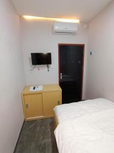 ein Schlafzimmer mit einem Bett und einem TV an der Wand in der Unterkunft Guesthouse Cempaka in Sibengkok