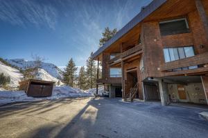 a house in the mountains with snow on the ground at Stylish 2BD Condo - Walk to Palisades! in Olympic Valley