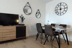 a dining room with a table and chairs and a clock at Les Géraniums, bel appartement rénové, proche plage et commerces in La Seyne-sur-Mer