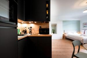 une cuisine avec des armoires noires et une chambre avec un lit dans l'établissement Renovated Chic Studio 5 Min to City Center-ID-160, à Luxembourg