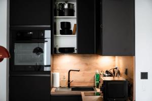 a kitchen with black cabinets and a sink and a microwave at Renovated Chic Studio 5 Min to City Center in Luxembourg