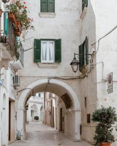 an alley with an archway in a building with green windows at Lena's Suites Bari Vecchia in Bari