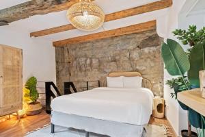 a bedroom with a white bed and a stone wall at Elegant 1BR Retreat in Peaceful Grund in Luxembourg