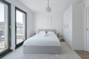Habitación blanca con cama y ventanas grandes. en Luxurious Duplex Penthouse in Center-Gare, en Luxemburgo