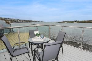 a table and chairs on a deck with the water at Waters Edge Ymyl Y Dwr in Y Felinheli
