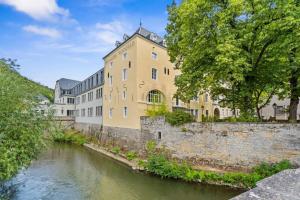 a large yellow building next to a river at Clausen Charm Contemporary Retreat ID210 in Luxembourg