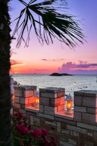 een zonsondergang over de oceaan met lichten op een stenen muur bij Hotel Castle in Ksamil