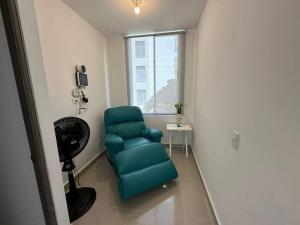 - un salon avec une chaise verte et une fenêtre dans l'établissement Apartamento Ocarro Villavicencio, à Villavicencio