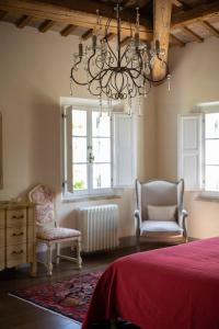 1 dormitorio con 1 cama, 2 sillas y lámpara de araña en La Monteduccia en Ostra Vetere