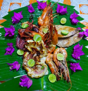 a plate of food with shrimp and fish on a banana leaf at Queen of Sheba Beach Lodge in Pongwe