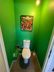une salle de bains verte avec des toilettes dans un mur vert. dans l'établissement Familial House in Calm Neighborhood Paris suburb, à Saint-Prix