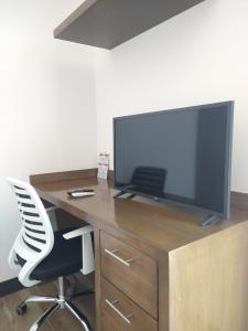 Elle comprend un bureau avec une télévision et une chaise blanche. dans l'établissement Suite Loft Amplio Nuevo Salida a CDMX 204A, à Querétaro