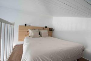 een witte slaapkamer met een groot bed met witte lakens bij Le Landifornia in Seignosse