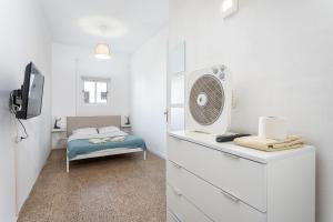 um pequeno quarto branco com uma cama e uma ventoinha em BLife Marya private rooms em Faro