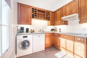 a kitchen with a washing machine and wooden cabinets at King's Cross 3BR - CityApartmentStay in London