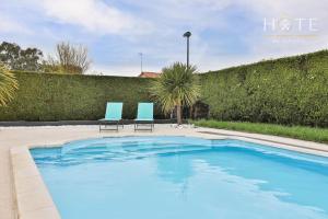 zwei blaue Stühle neben einem Swimmingpool in der Unterkunft La Vinière - Villa avec piscine in Saint-Hilaire-de-Talmont