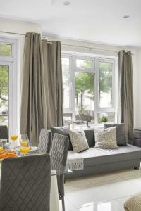 - un salon avec un canapé et quelques fenêtres dans l'établissement Paddington with Balcony - CityApartmentStay, à Londres