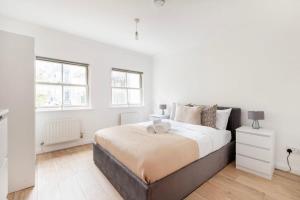 a white bedroom with a bed and two windows at Old Street - 4BR Townhouse with Patio - CityApartmentStay in London