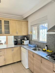 a kitchen with wooden cabinets and a sink at Anfora Villaları in Belek