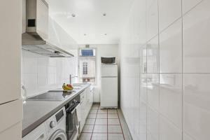 cocina con electrodomésticos blancos y nevera blanca en Trocadero & Arc de Triomphe with Balcony - CityApartmentStay, en París