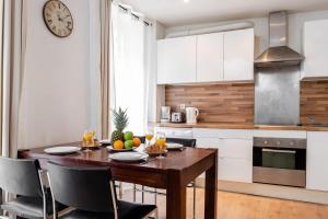 a kitchen with a wooden table with chairs and a clock at Champ de Mars & Rue de Grenelle - CityApartmentStay in Paris