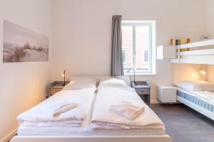 a white bedroom with two beds and a window at Steilküsten Oase in Schilksee