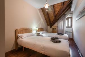 two beds in a room with wooden ceilings at Casa Garona by SeaMount Rentals in Bossost