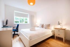 Habitación blanca con cama blanca y escritorio. en Shoreditch Park & Islington - CityApartmentStay en Londres