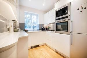 a kitchen with white cabinets and a refrigerator at Shoreditch Park & Islington - CityApartmentStay in London