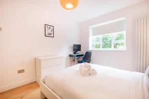 a white bedroom with a bed with two towels on it at Shoreditch Park & Islington - CityApartmentStay in London