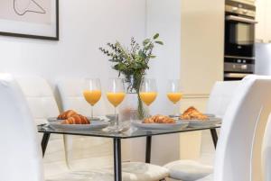 uma mesa com três copos de sumo de laranja e croissants em Notting Hill & Hyde Park - CityApartmentStay em Londres
