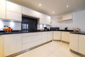 a kitchen with white cabinets and a bowl of fruit on the counter at Notting Hill & Hyde Park - CityApartmentStay in London